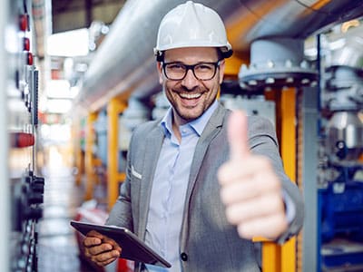 Homme souriant avec casque de sécurité et tablette, symbolisant la maîtrise des compétences en efficacité professionnelle grâce aux formations Leaderseed.