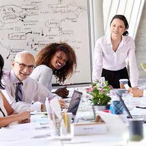 Une équipe en pleine formation en management et leadership, collaborant autour d’une table avec un tableau blanc en arrière-plan, dans le cadre des formations proposées par Leaderseed.