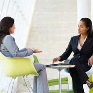 Deux femmes professionnelles en discussion dans un cadre moderne, symbolisant le coaching professionnel proposé par Leaderseed pour cadres, managers et collaborateurs en entreprise.