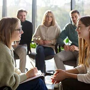 Un groupe de professionnels lors d’une séance de mentorat et de supervision, avec une mentor prenant des notes et guidant une participante, illustrant les accompagnements personnalisés proposés par Leaderseed.