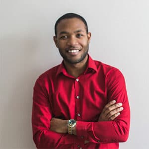 Un jeune homme professionnel en chemise rouge, souriant avec confiance, symbolisant la réussite personnelle et professionnelle grâce aux solutions proposées par Leaderseed.